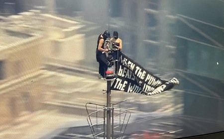 Two people climb to the top of Empire State Building with massive banner